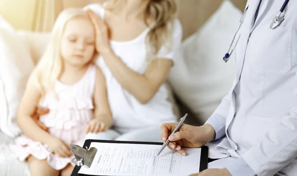 Dokter en patiënt. Kinderarts die klembord gebruikt terwijl ze het kleine meisje onderzoekt met haar moeder thuis. Ziek en ongelukkig kind bij medisch onderzoek — Stockfoto