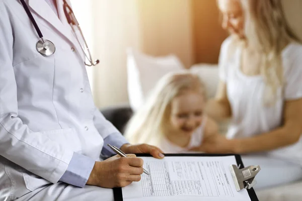医者と患者だ。小児科医は、自宅で母親と一緒に小さな女の子を検討しながら、クリップボードを使用して.医学の試験で幸せなかわいい白人の子供。医学の概念 — ストック写真