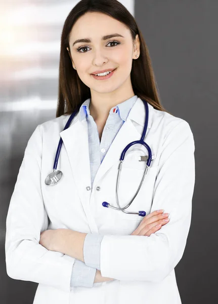 Usmívající se mladá žena-doktor stojí na slunné klinice uvnitř — Stock fotografie