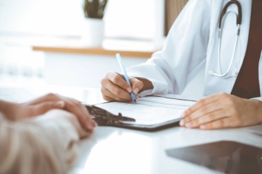 Bilinmeyen kadın-doktor hastaya danışmanlık yaparken başvuru formu dolduruyor. Tıp konsepti