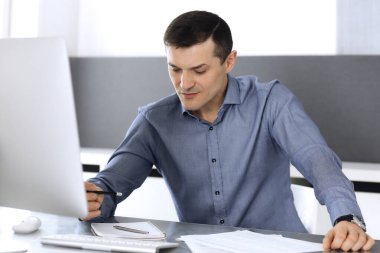 Modern ofiste bilgisayarla çalışan bir iş adamı. İş yerindeki erkek girişimcinin ya da şirket müdürünün vesikalığı. İş konsepti