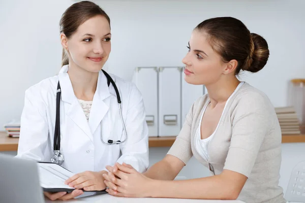 El médico y el paciente están sentados y discutiendo los resultados del examen de salud en el consultorio clínico. Salud, medicina y conceptos de buenas noticias — Foto de Stock