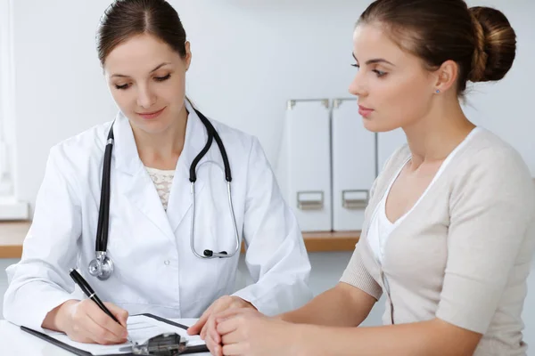 El médico y el paciente están sentados y discutiendo los resultados del examen de salud en el consultorio clínico. Salud, medicina y conceptos de buenas noticias — Foto de Stock