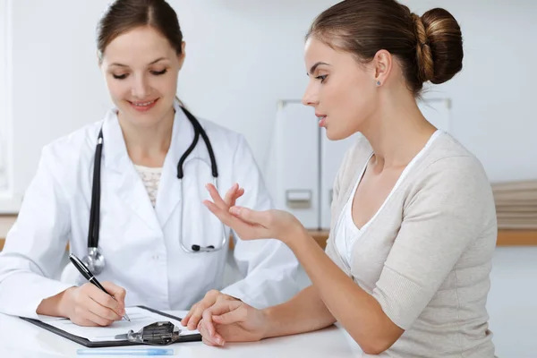 El médico y el paciente están sentados y discutiendo los resultados del examen de salud en el consultorio clínico. Salud, medicina y conceptos de buenas noticias — Foto de Stock