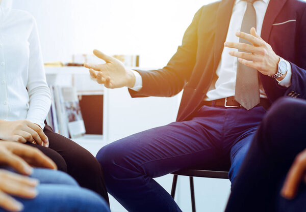 Группа людей, сидящих в кругу во время терапии в офисе. Встреча бизнес-команды, участвующей в тренинге