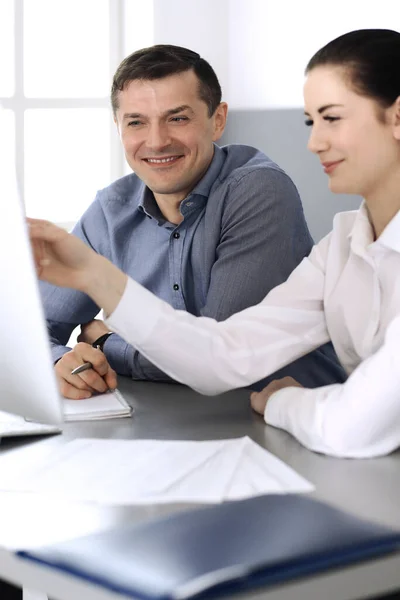 Joyeux homme d'affaires souriant et femme qui travaille avec l'ordinateur dans un bureau moderne. Tête d'affiche à la réunion ou au travail. Travail d'équipe, partenariat et concept d'entreprise Image En Vente