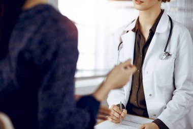 Doktor ve hasta güneşli klinikte otururken sağlık muayenesini tartışıyorlar. Tıp konsepti