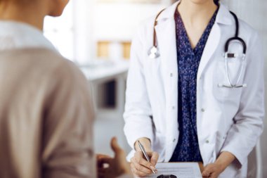 Doktor ve hasta güneşli klinikte otururken sağlık muayenesini tartışıyorlar. Tıp konsepti