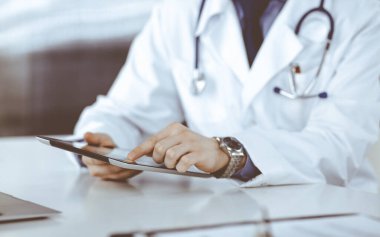 Bilinmeyen erkek doktor klinikteki tablet bilgisayarla yakın planda çalışıyor. İşteki genç doktor. Mükemmel sağlık hizmeti, tıp konsepti