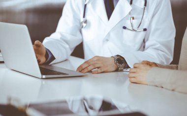 Bilinmeyen erkek doktor ve hasta kadın klinikte oturup dizüstü bilgisayar kullanırken bir şeyler tartışıyorlar. Hastanedeki en iyi sağlık hizmeti, ilaç, salgın durdurma.