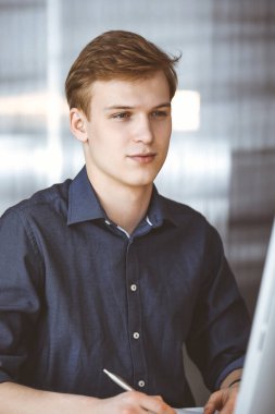 Bilgisayarla çalışan genç sarışın iş adamı. Girişim işi, başarı için çok çalışmak ve zamanın dışında çalışmak demektir.