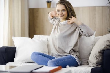 Mutlu esmer kadın ellerini başının arkasına koyuyor koltuğa yaslanıyor Avrupalı kadın tembel hafta sonunun keyfini çıkarıyor ya da sıcak oturma odasında tatilin tadını çıkarıyor, ev hanımı ev işi yaptıktan sonra rahatlıyor.