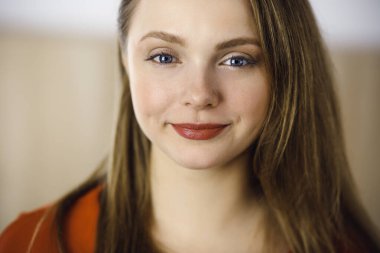 Zeki, kendinden emin, gülümseyen, Avrupalı bir kadının kollarını kavuşturup evinde dikilirken çekilmiş bir fotoğrafı. Çekici genç kız öğrenci serbest çalışan, kırmızı giyinmiş, kameraya bakıyor.