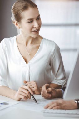 İş adamları güneşli bir ofiste otururken bir şeyler tartışıyorlar. Erkek arkadaşıyla konuşurken iş kadınına odaklan.