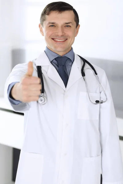 Arzt lächelt fröhlich in die Kamera, Daumen hoch. Perfekte medizinische Versorgung in der Klinik. Glückliche Zukunft in Medizin und Gesundheitswesen — Stockfoto