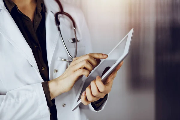 Doctora desconocida usando tableta en clínica soleada. Concepto de medicina — Foto de Stock