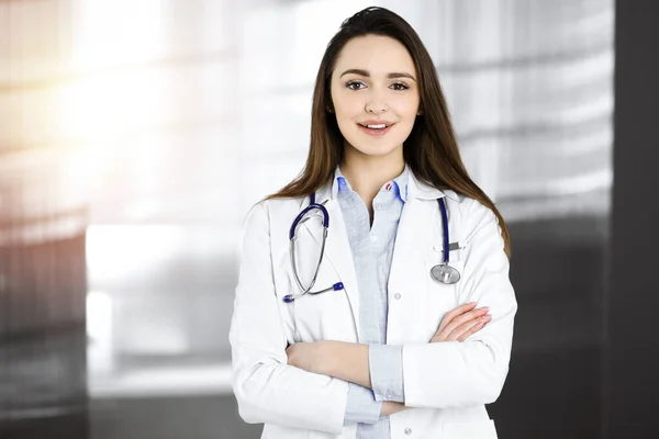 Lächelnde junge Ärztin steht in sonniger Klinik — Stockfoto