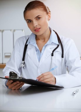 Kadın doktor klinikte oturuyor ve çalışıyor. Kadın doktor portresi. Tıp konsepti