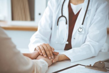 Kadın hastasına güvence veren kimliği belirsiz kadın doktorun elleri, yakın plan. Tıp konsepti