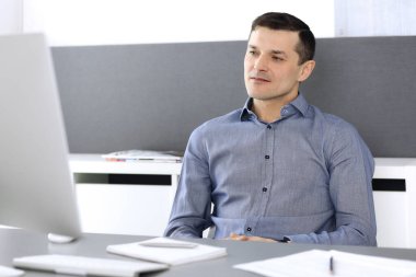 Modern ofiste bilgisayarla çalışan bir iş adamı. İş yerindeki erkek girişimcinin ya da şirket müdürünün vesikalığı. İş konsepti