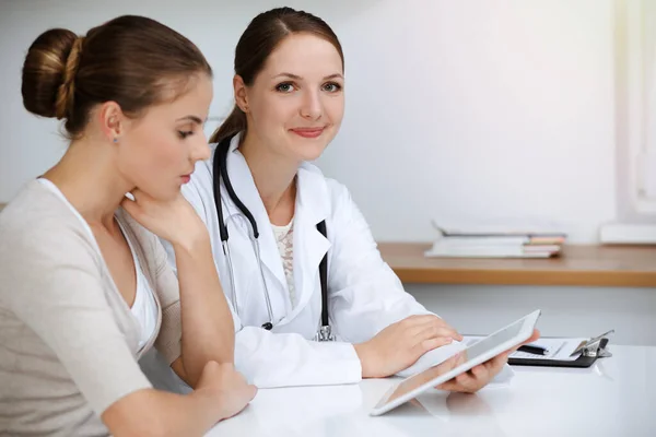 Γιατρός και ασθενής κάθονται και συζητούν τα αποτελέσματα των εξετάσεων υγείας κατά τη χρήση του υπολογιστή tablet. Ιατροφαρμακευτική περίθαλψη, ιατρική και καλές ειδήσεις — Φωτογραφία Αρχείου