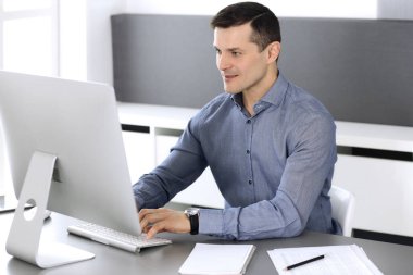 Modern ofiste bilgisayarla çalışan bir iş adamı. İş yerindeki erkek girişimcinin ya da şirket müdürünün vesikalığı. İş konsepti