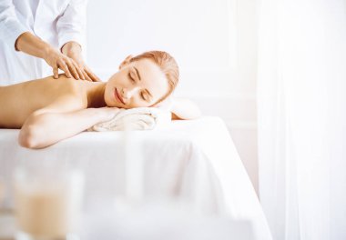 Güneşli spa merkezinde sırt masajından hoşlanan güzel bir kadın. Tıpta rahatlatıcı tedavi kavramı