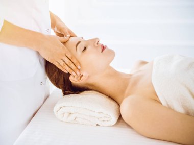 Güneşli kaplıcalarda yüz masajından hoşlanan güzel bir kadın.