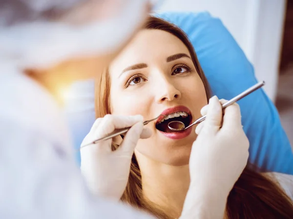 在阳光灿烂的牙科诊所接受牙医检查的带着正牙托的年轻女子的微笑。健康的牙齿和医学概念 — 图库照片