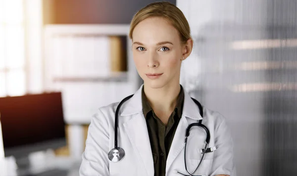 Allegro sorridente medico donna in piedi in clinica soleggiata. Ritratto di donna medico amichevole. Servizio medico perfetto in ospedale. Concetto di medicina — Foto Stock