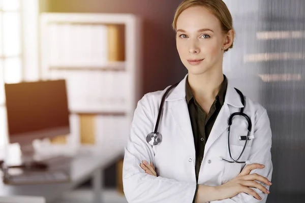 Allegro sorridente medico donna in piedi in clinica soleggiata. Ritratto di donna medico amichevole. Servizio medico perfetto in ospedale. Concetto di medicina — Foto Stock