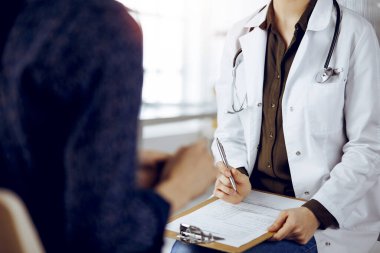 Doktor ve hasta güneşli klinikte otururken sağlık muayenesini tartışıyorlar. Tıp konsepti