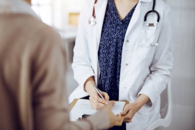 Doktor ve hasta güneşli klinikte otururken sağlık muayenesini tartışıyorlar. Tıp konsepti