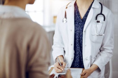 Doktor ve hasta güneşli klinikte otururken sağlık muayenesini tartışıyorlar. Tıp konsepti