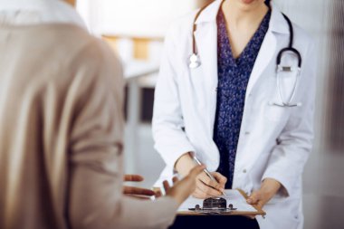 Doktor ve hasta güneşli klinikte otururken sağlık muayenesini tartışıyorlar. Tıp konsepti