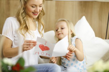 Anneler Günün kutlu olsun. Çocuk kızı annesini tebrik ediyor ve ona kalp çizimiyle kartpostal atıyor. Aile ve çocukluk kavramları