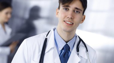 Modern klinikte dostane genç bir erkek doktor elinde bir panoyla dikiliyor. Bayan meslektaşım, doktorların arka planında ilaç kayıtları doldurmakla meşgul. Tıp konsepti