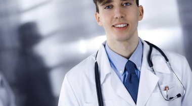 Modern klinikte dostane genç bir erkek doktor elinde bir panoyla dikiliyor. Bayan meslektaşım, doktorların arka planında ilaç kayıtları doldurmakla meşgul. Tıp konsepti