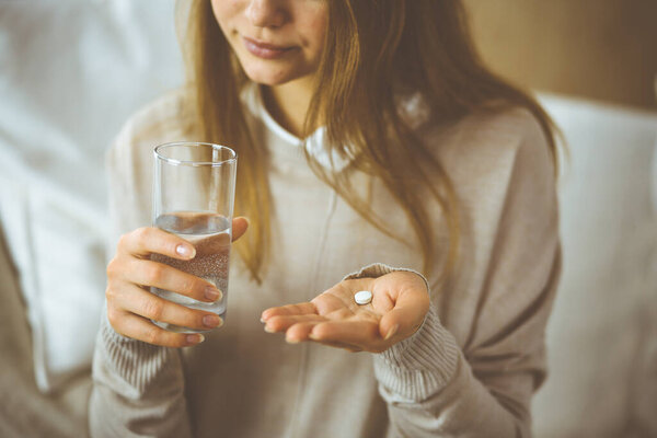 Close-up woman holding pills time to take medications, cure for headache, high blood pressure or cholesterol level remedy pain killer drugs. Stay at home concept during Coronavirus pandemic and self