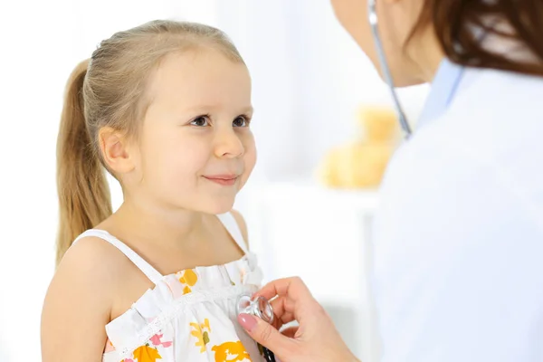 Doutor examinando uma menina por estetoscópio. Paciente de criança sorridente feliz em inspeção médica habitual. Conceitos de medicina e saúde — Fotografia de Stock