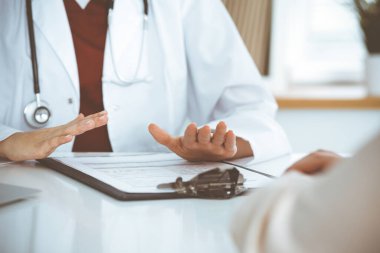 Bilinmeyen kadın doktor ve hasta klinikteki masada otururken bir şey tartışıyorlar, yakın plan. Tıp konsepti