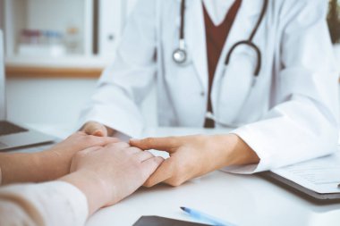 Kadın hastasına güvence veren kimliği belirsiz kadın doktorun elleri, yakın plan. Tıp konsepti