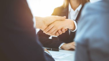 İş adamları toplantıyı bitirmek ya da güneşli ofiste pazarlık yapmak için el sıkışıyor. İş tokalaşması ve ortaklık kavramları