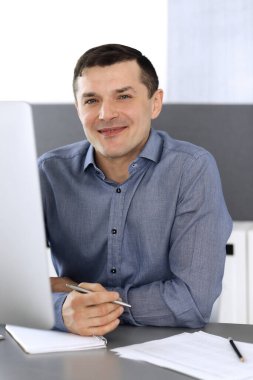 Modern ofiste bilgisayarla çalışan bir iş adamı. İş yerindeki erkek girişimcinin ya da şirket müdürünün vesikalığı. İş konsepti