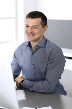 Modern ofiste bilgisayarla çalışan bir iş adamı. İş yerindeki erkek girişimcinin ya da şirket müdürünün vesikalığı. İş konsepti