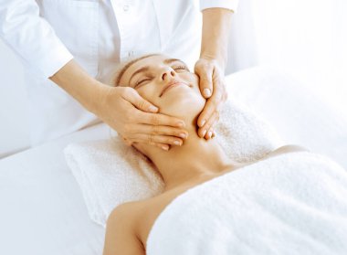 Güzeller güzeli sarışın kadın spa merkezinde yüz masajından hoşlanıyor. Tıp ve güzellik kavramlarında rahatlatıcı tedavi