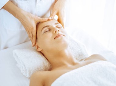 Güzeller güzeli sarışın kadın spa merkezinde yüz masajından hoşlanıyor. Tıp ve güzellik kavramlarında rahatlatıcı tedavi