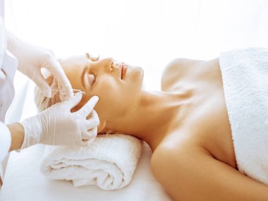 Güzellik uzmanı elleri klinikte şırıngalı kadın sarışına güzellik prosedürü uyguluyor. Kozmetik tıp ve cerrahi, güzellik enjeksiyonları konsepti