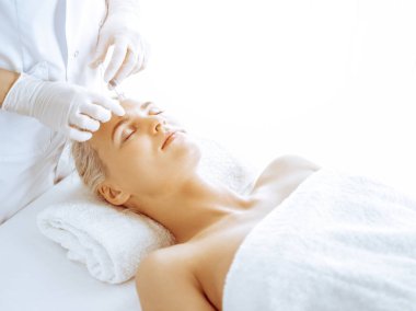 Güzellik uzmanı elleri klinikte şırıngalı kadın sarışına güzellik prosedürü uyguluyor. Kozmetik tıp ve cerrahi, güzellik enjeksiyonları konsepti