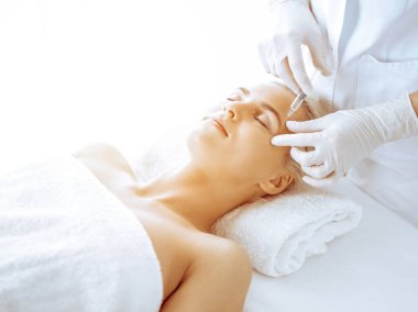 Güzellik uzmanı elleri klinikte şırıngalı kadın sarışına güzellik prosedürü uyguluyor. Kozmetik tıp ve cerrahi, güzellik enjeksiyonları konsepti